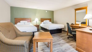 A hotel room with two beds, a desk, a chair, and a small table.
