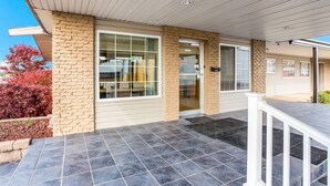 A building with a covered entrance, a stone facade, and a tiled patio area.