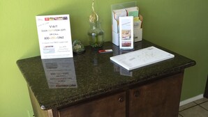 Un mostrador de recepción con pared verde, encimera de mármol y mueble de madera. Hay un cartel que ofrece una tarjeta de fidelización y un número de teléfono.