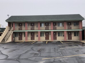 Two-story motel with a central entrance and flat roof, featuring double doors and a set of stairs.