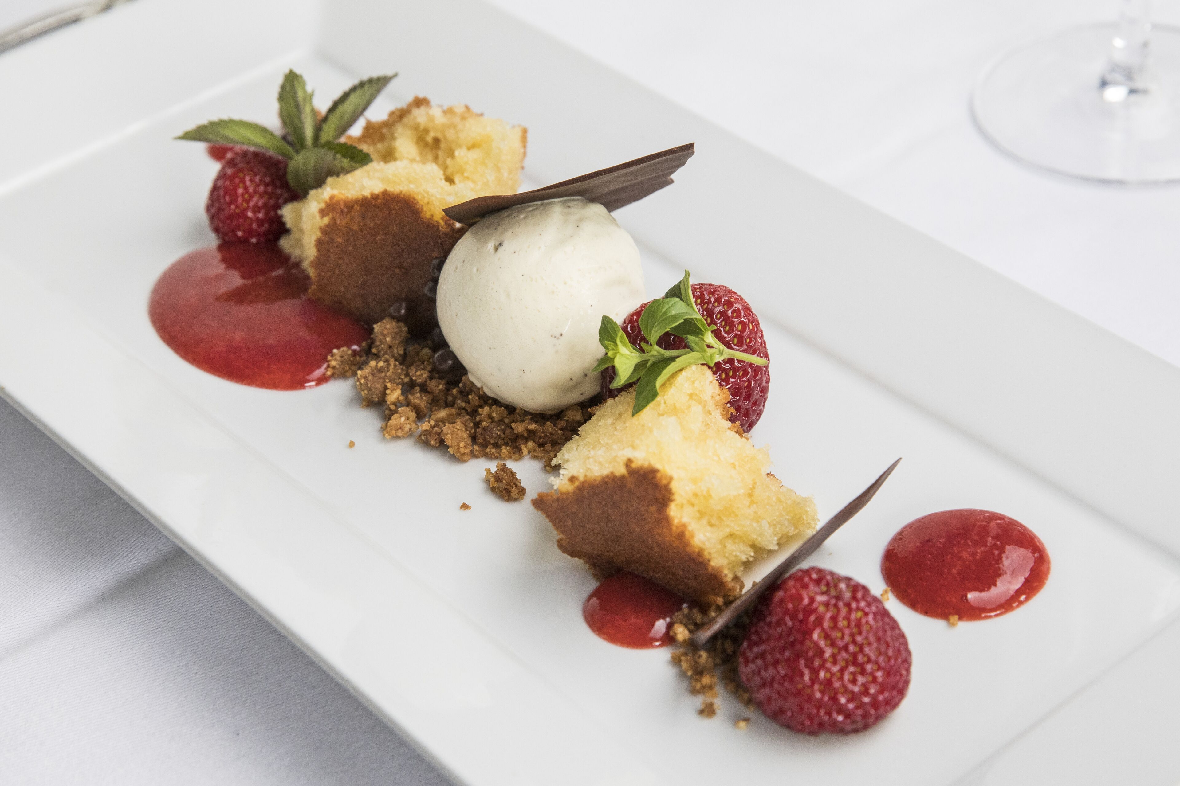 A dessert plate with cake, ice cream, strawberries, and chocolate sauce.