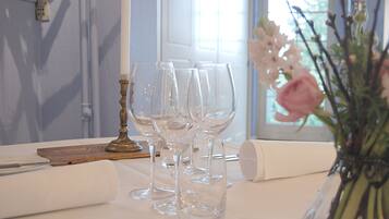 A table set with clear wine glasses, a candle holder, and a rolled napkin.