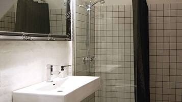 Un bagno con un lavandino bianco, uno specchio e una doccia con tenda nera.