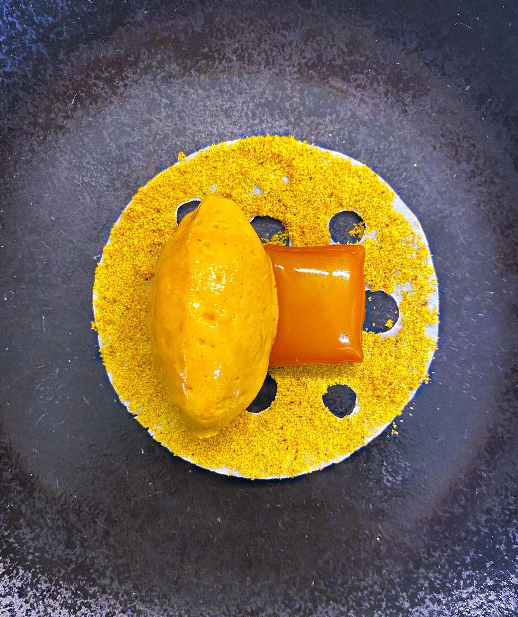A yellow substance on a dark surface with a hole in the center.