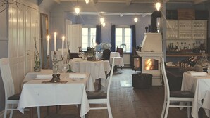 Un espace repas avec des tables dressées pour le repas, une cheminée et un bar avec des bouteilles.