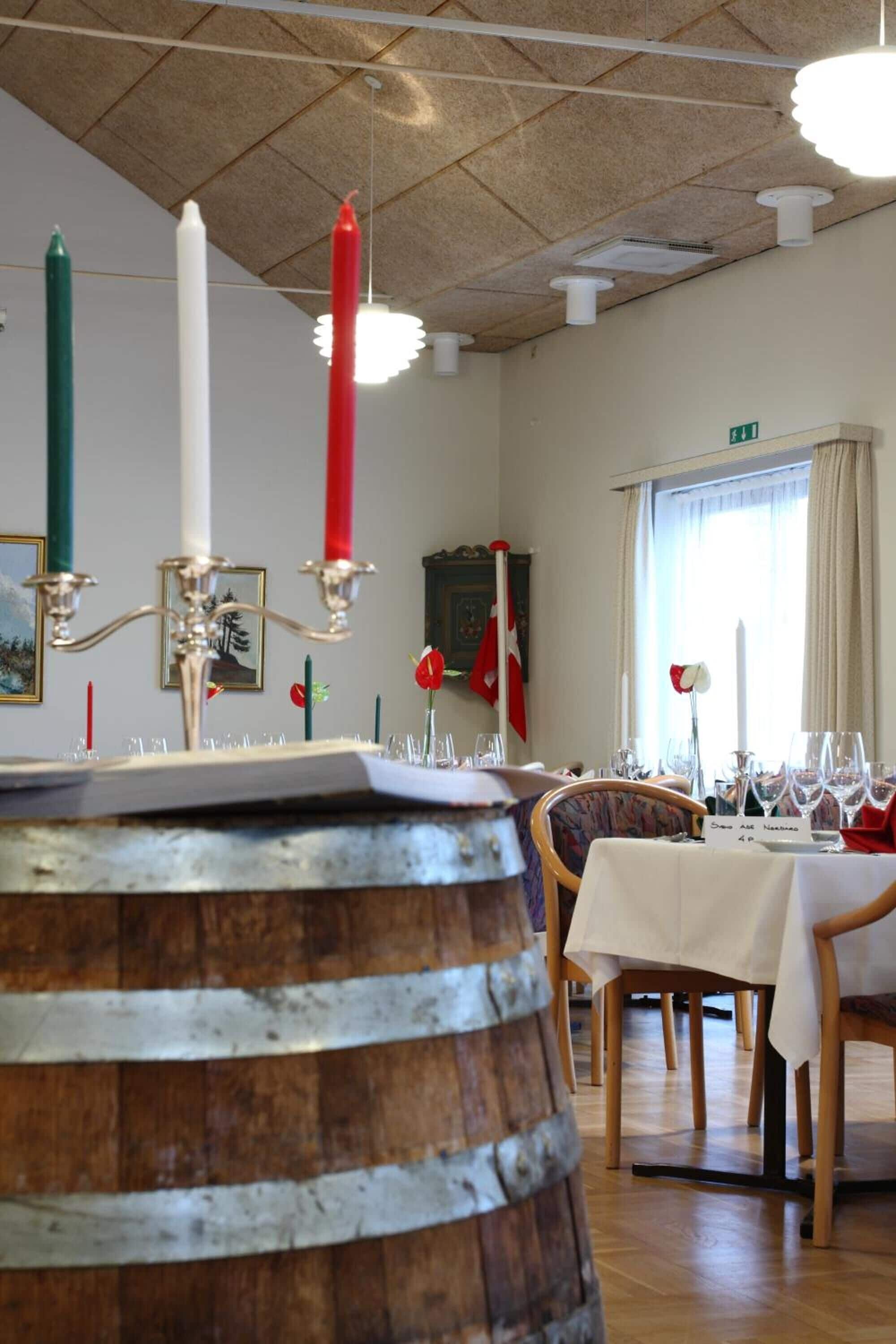 A dining area with a wooden barrel, a candelabra with candles, and a table set for two.