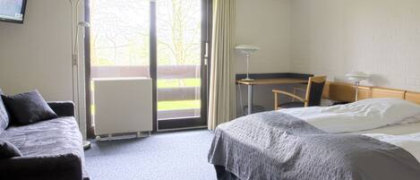 A hotel room with a bed, a desk, a chair, and a TV on the wall.