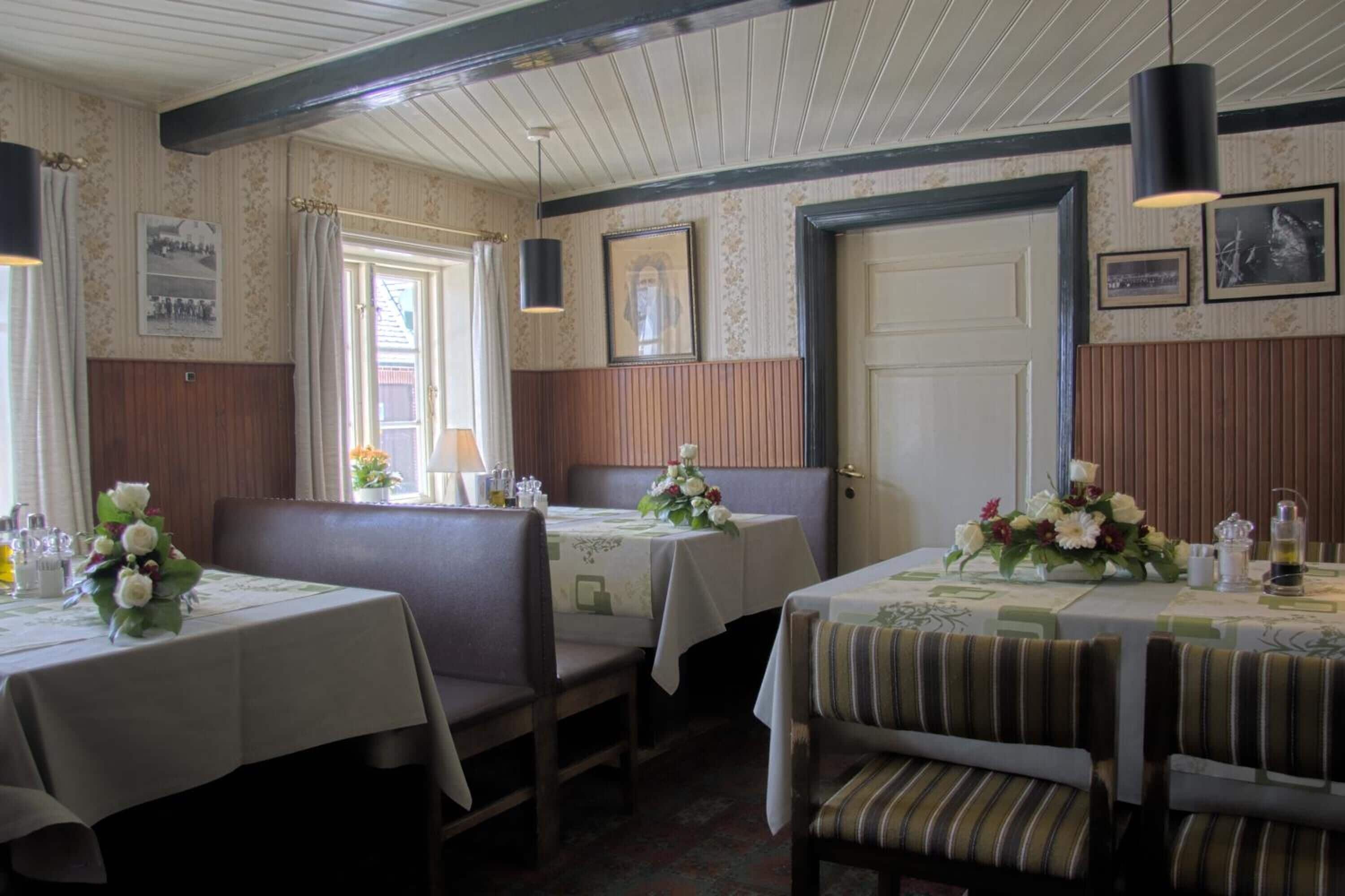 A dining area with booths and tables, wooden paneling, and framed pictures on the walls.
