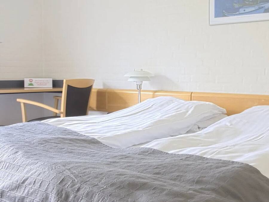 A hotel room with a bed, two bedside tables, a desk, and a chair.