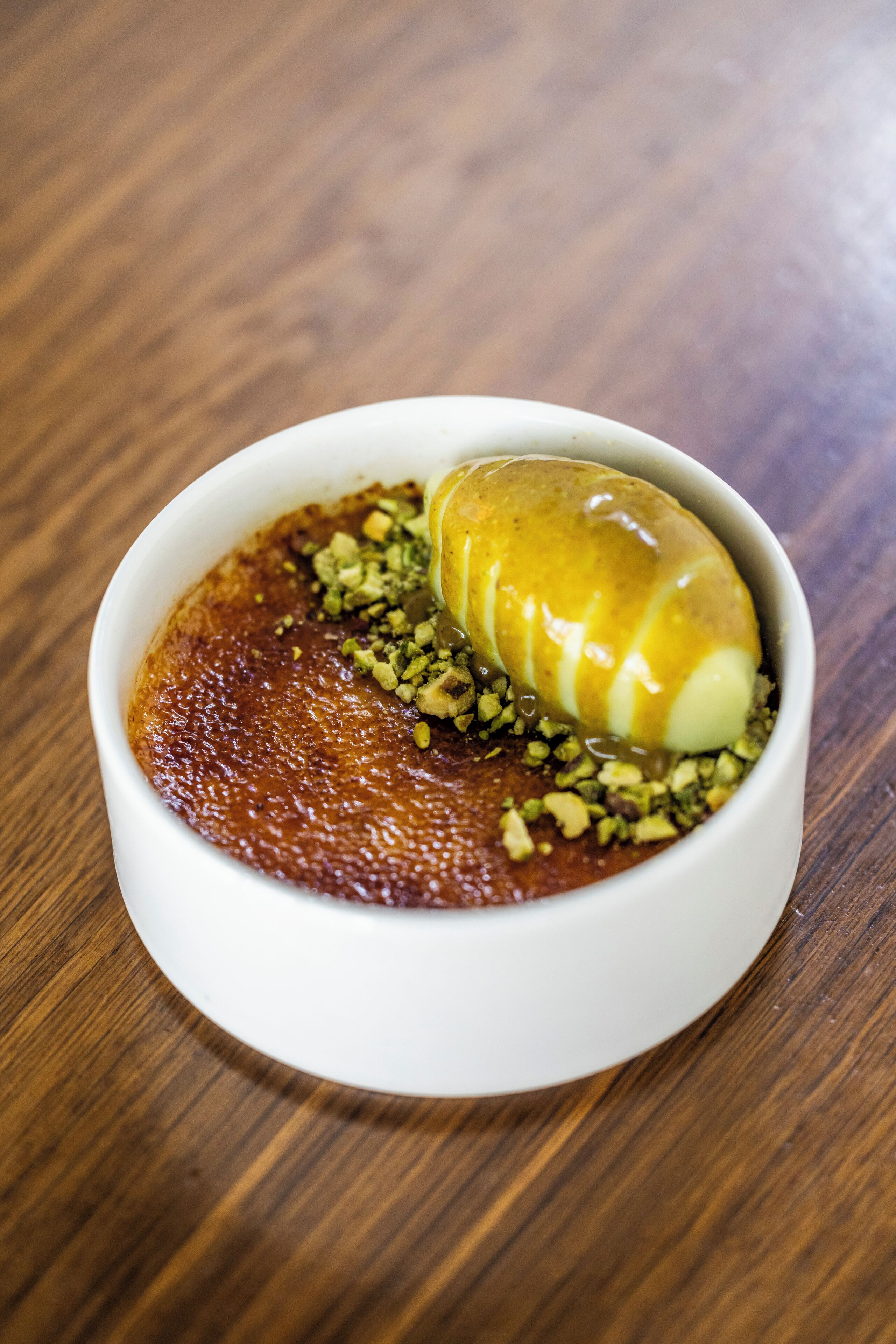 Un postre en un tazón blanco sobre una mesa de madera.