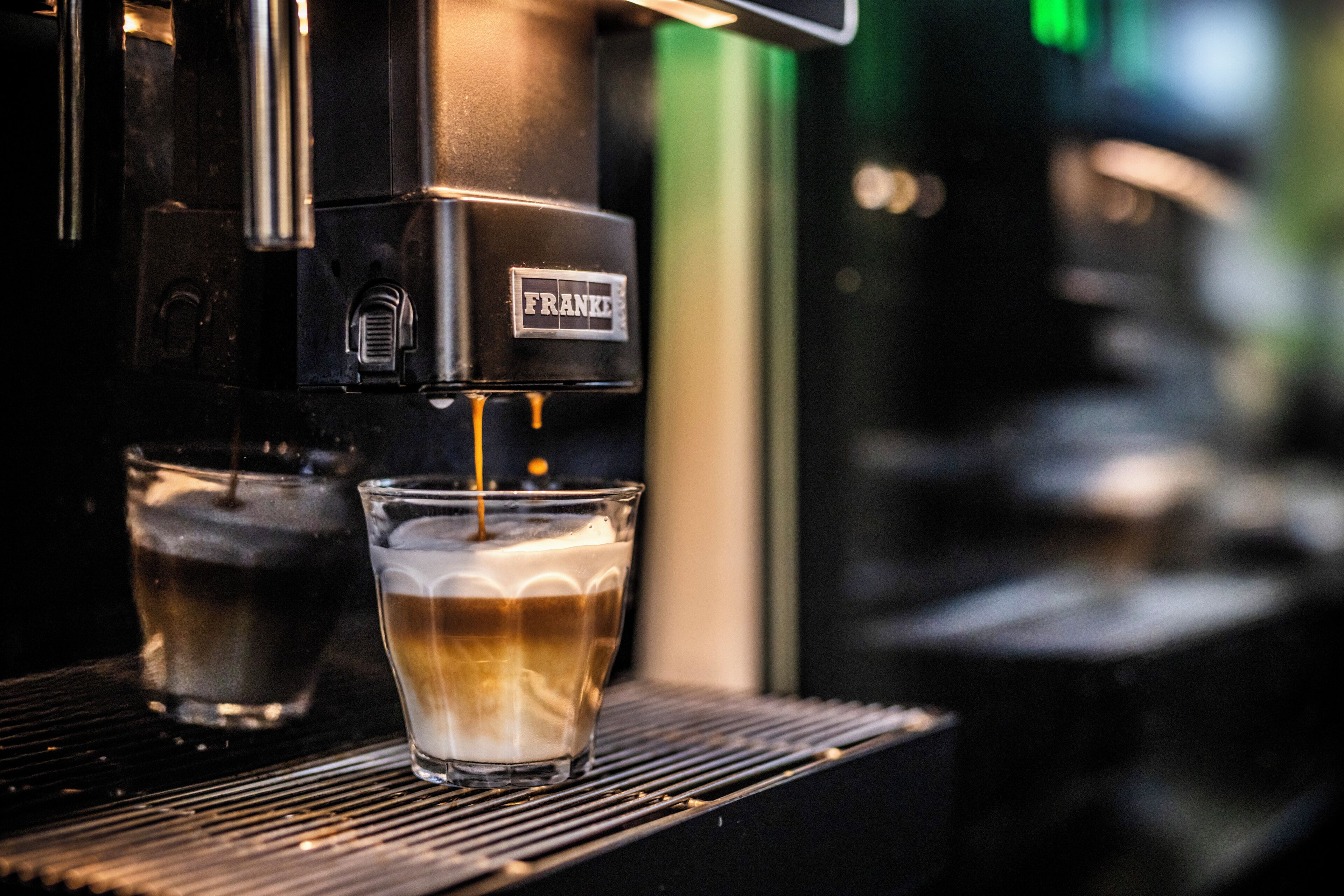 A coffee machine dispensing espresso into a glass.