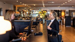A bar area with a long counter, computers, and a bar stocked with bottles. - Hotel Svanen, Stays & BW Signature Collection (Billund)
