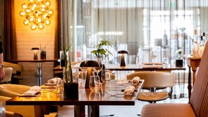 A restaurant setting with tables set for dining, featuring glassware, napkins, and a potted plant. - Hotel Svanen, Stays & BW Signature Collection (Billund)