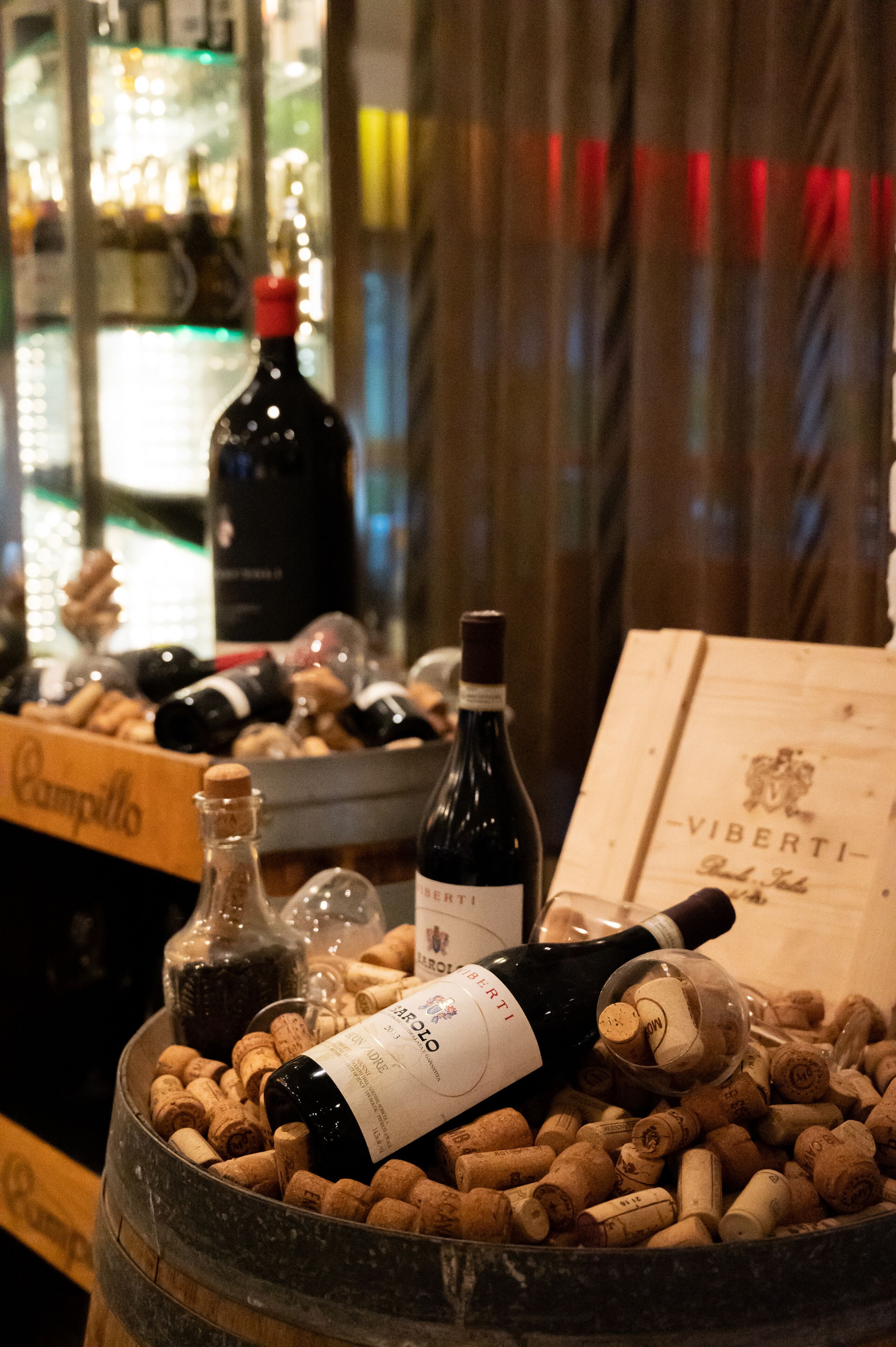 Un barril lleno de corchos y botellas de vino, incluyendo una botella destacada con la etiqueta "VIBERTI".
