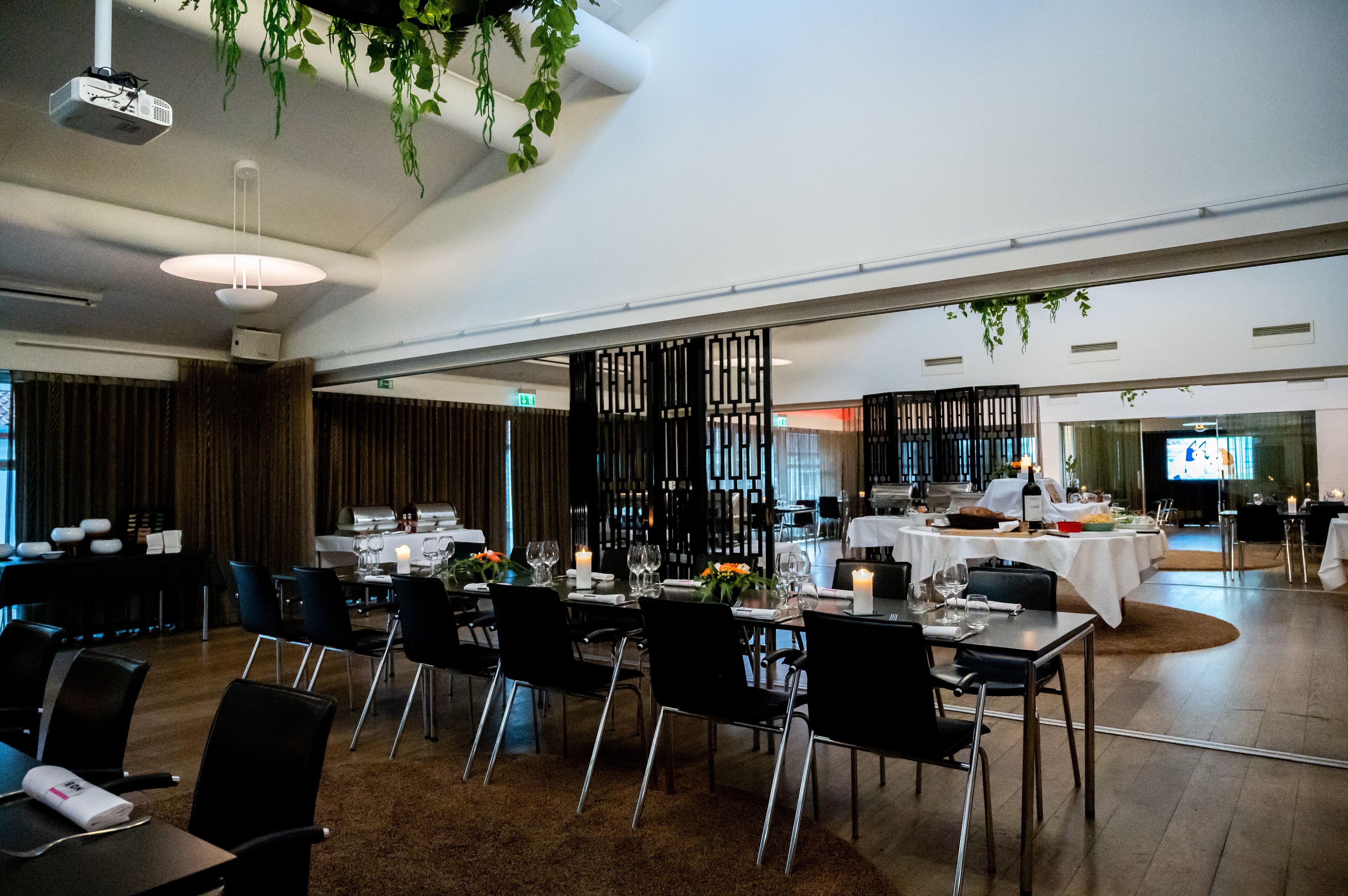A spacious dining area with multiple tables set for a meal, featuring modern decor and ambient lighting.