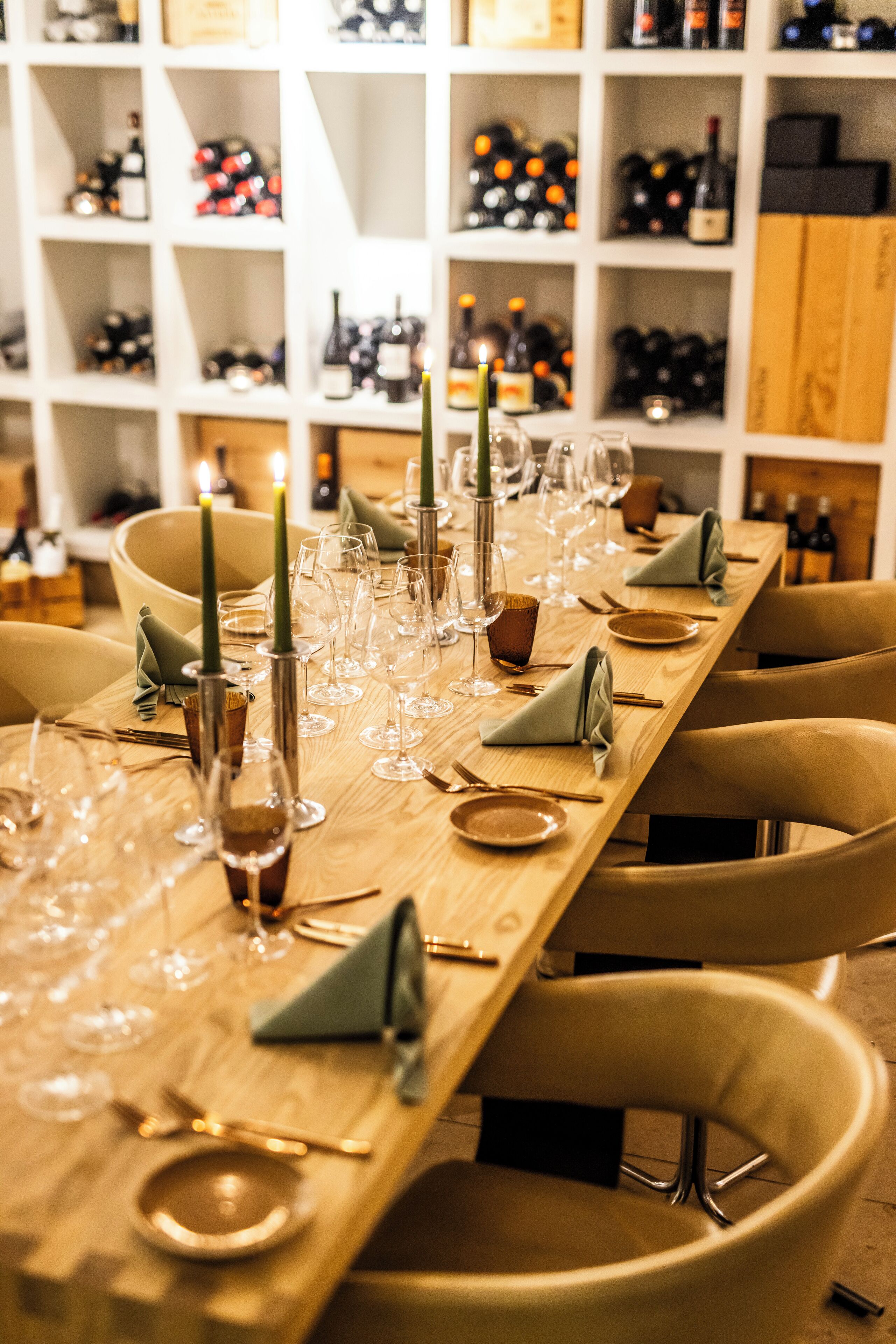 A long dining table set with wine glasses, plates, and cutlery, flanked by chairs.