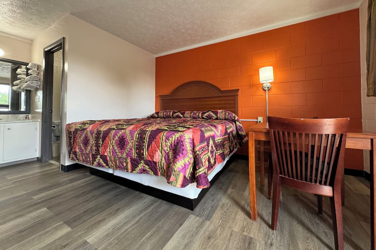 A hotel room with a bed, a desk, and a chair.