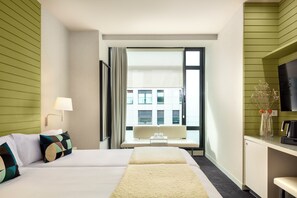 A hotel room with a bed, a desk, a TV, and a window with a view of buildings. - Hotel Miro (Bilbao)