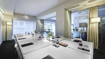 A modern conference room with a long table, water bottles, and a laptop.