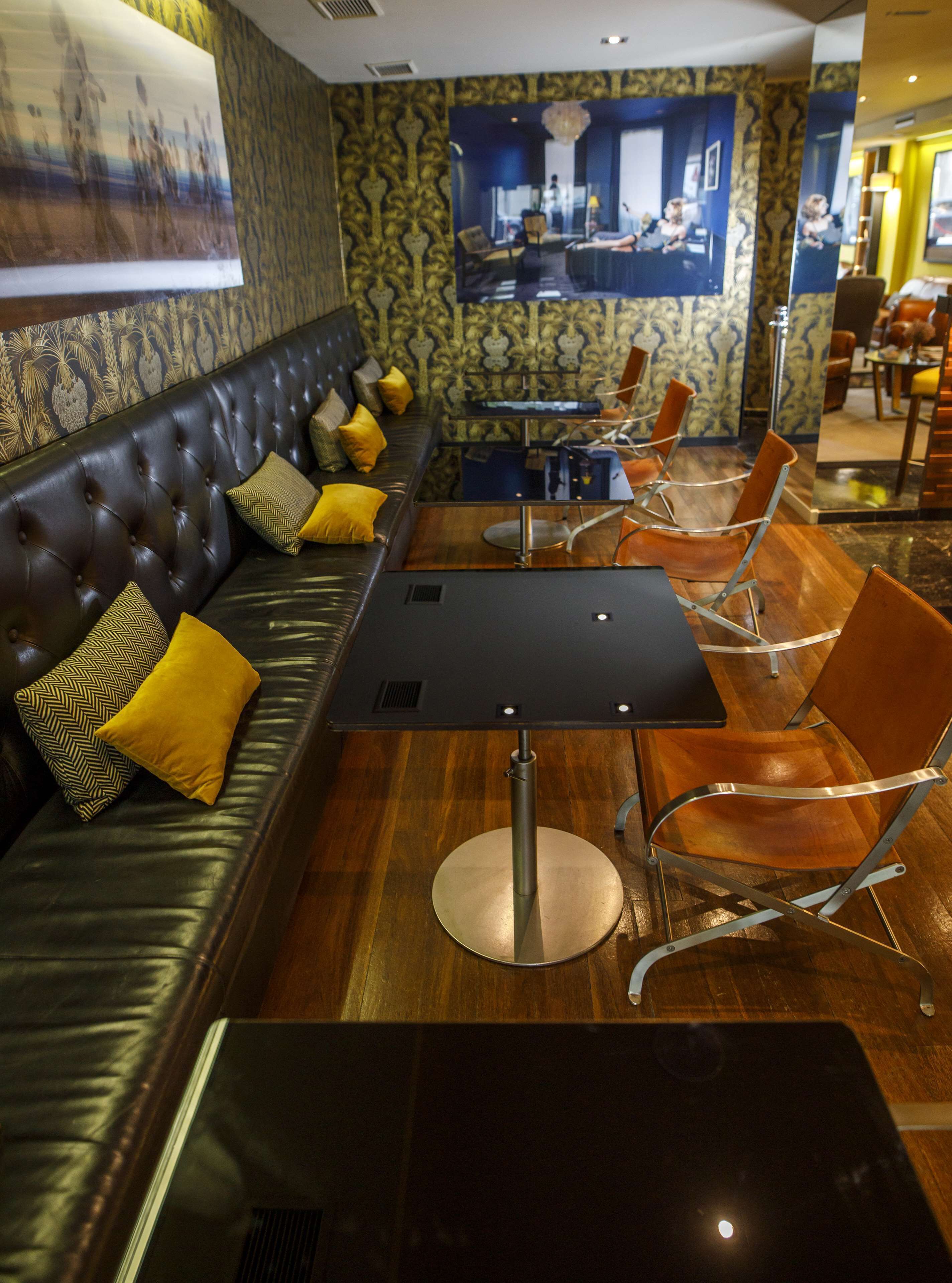 Un área de estar moderna con un sofá de cuero, sillas de metal y una mesa central.
