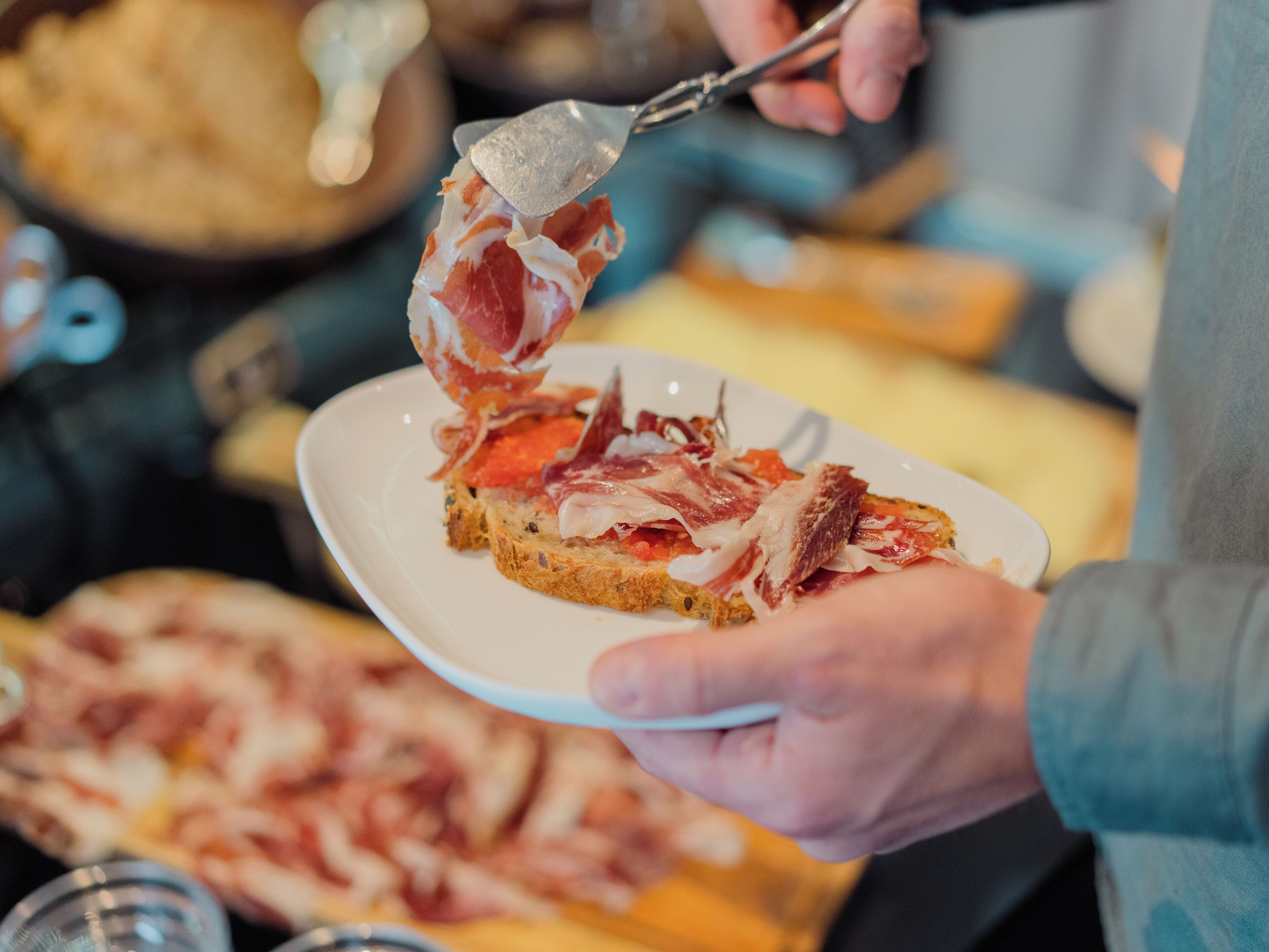 Una persona sostiene un plato con una rebanada de pan cubierta de carne y tomate.