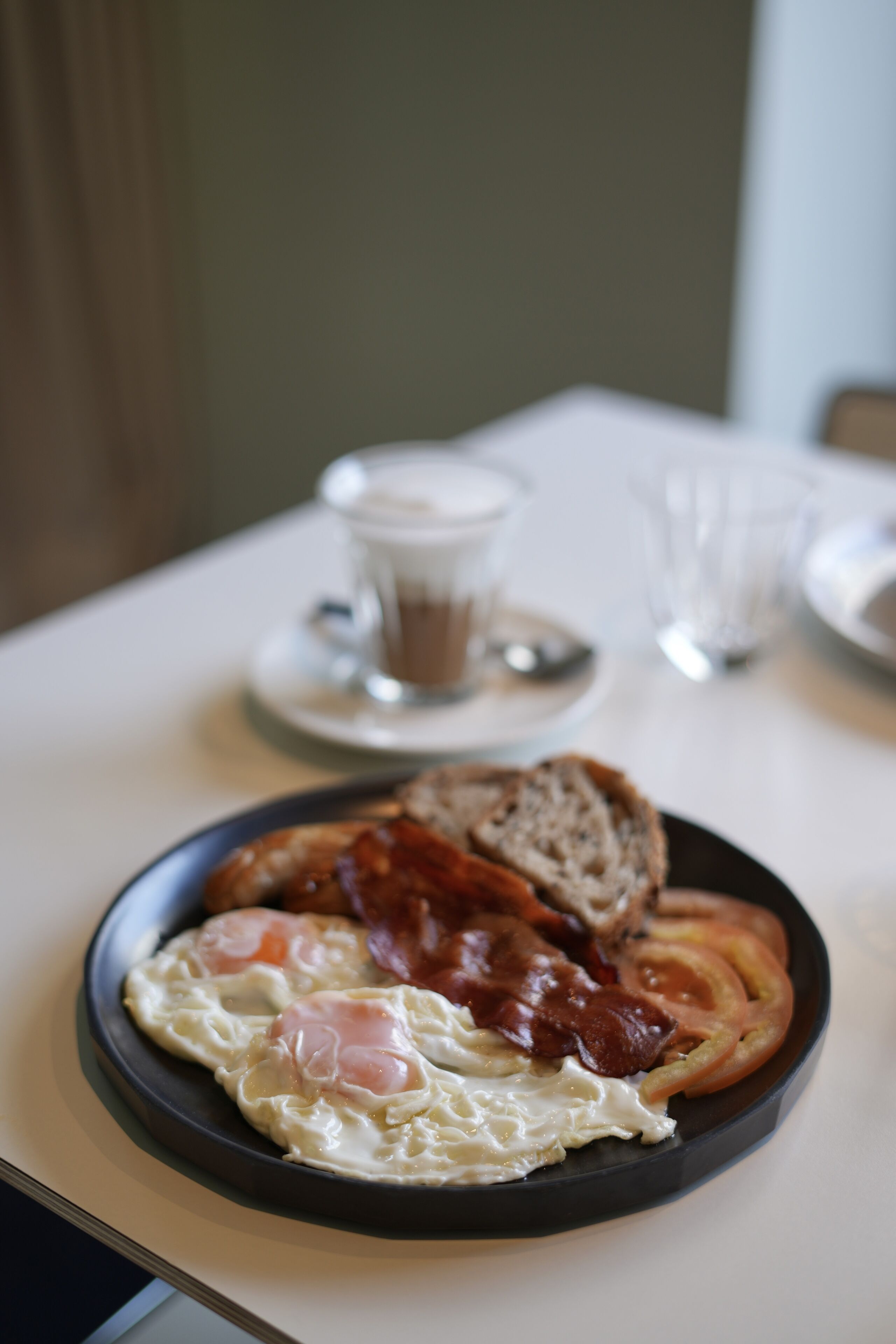 Un piatto da colazione con uova, pancetta e pane tostato su un tavolo.