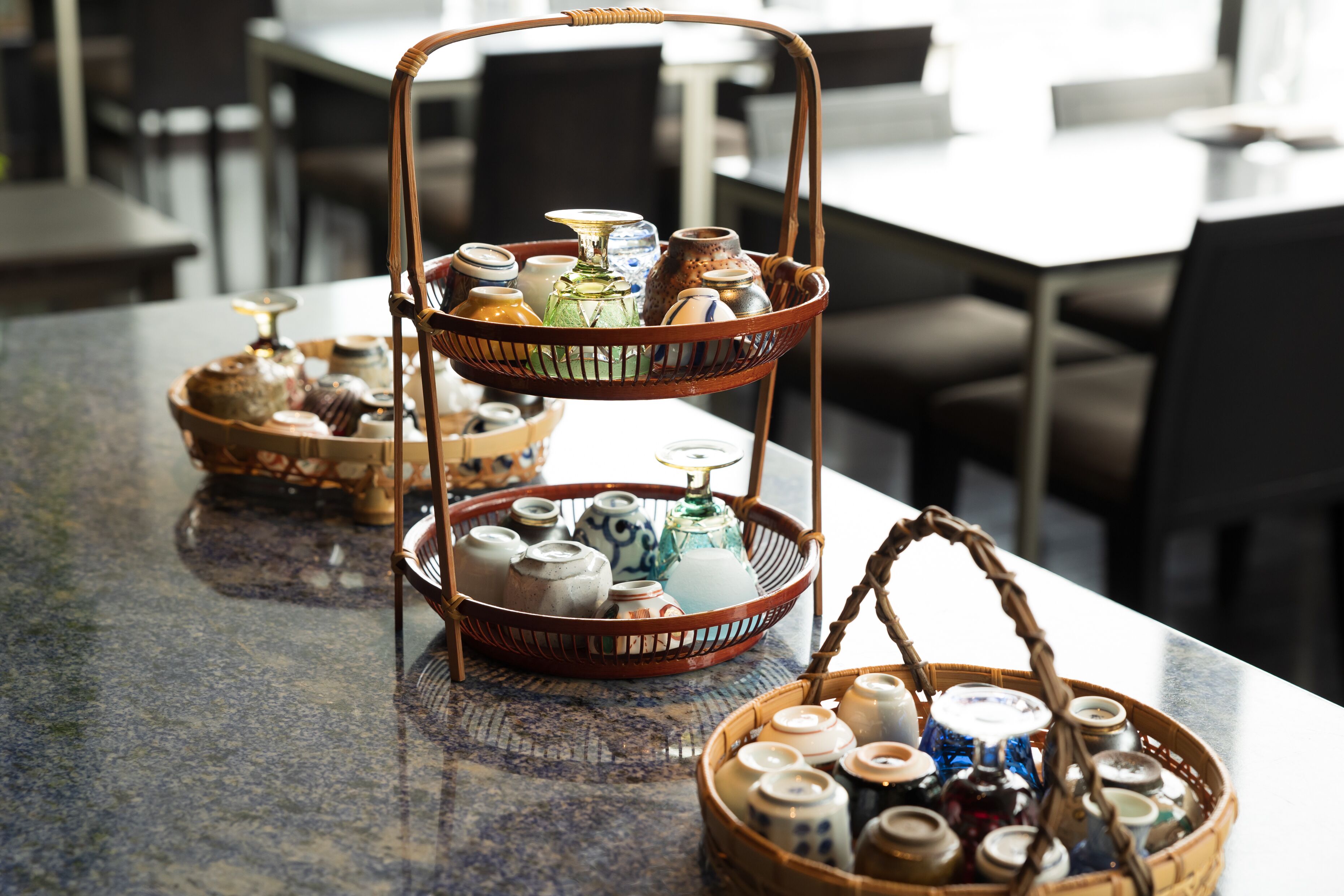 A table with two wicker baskets containing ceramic mugs and glassware.