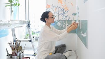 A person painting a wall with floral designs.