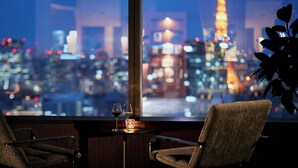 Vista de la Torre Eiffel desde una ventana, con dos sillas y una mesa con vasos.