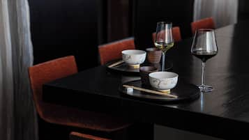 A dining table with bowls, chopsticks, and wine glasses.