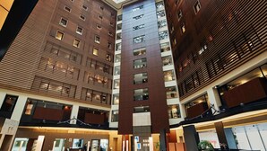Un moderno vestíbulo de hotel con techo alto, un atrio central y una zona de piscina.