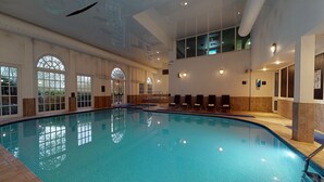 An indoor swimming pool with clear glass walls, a tiled floor, and a high ceiling with visible ductwork. - Village Hotel St David's, Nr Chester (Deeside)
