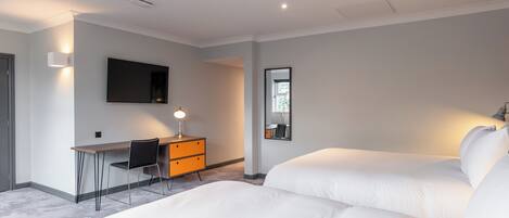 A modern hotel room with a large bed, a desk with a chair, a flat-screen TV, and a mirror.