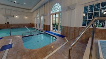 Une piscine intérieure avec un revêtement de sol carrelé, un tapis bleu et une rambarde métallique.