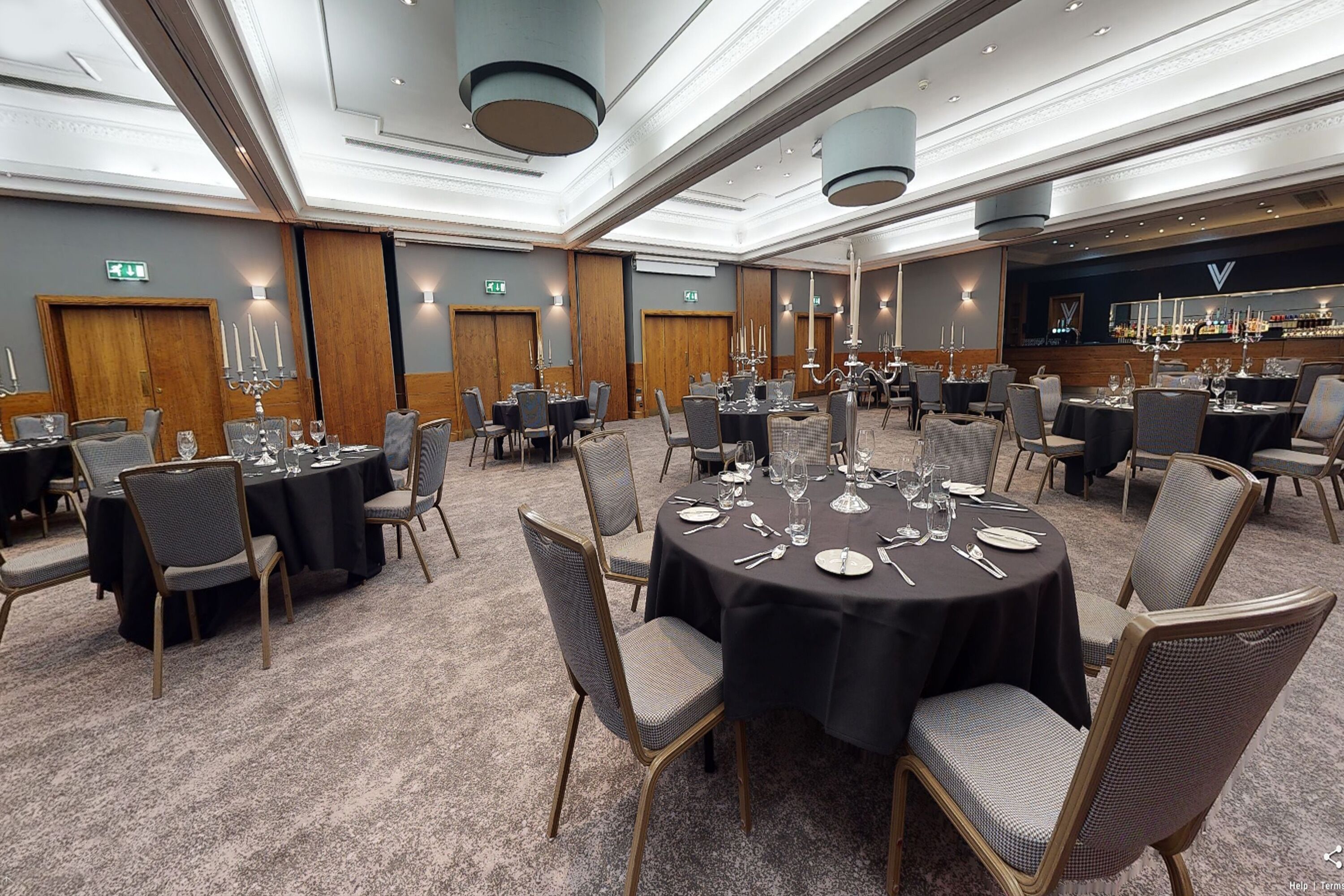 A conference room with round tables set for dining, equipped with chairs and table settings.