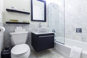 A modern bathroom with a toilet, sink, and bathtub. There are shelves above the sink and a mirror above the toilet. - Eurostars Wall Street (New York)