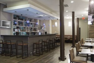 A modern bar area with a counter, bar stools, and seating for diners.