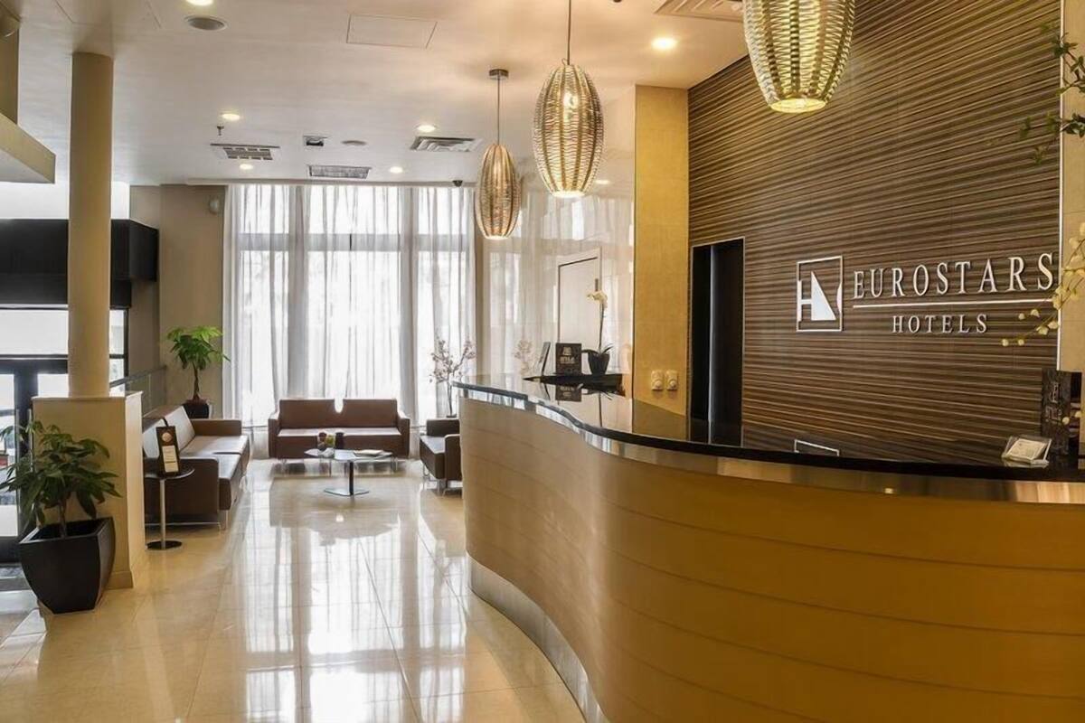 Un moderno vestíbulo de hotel con mostrador de recepción, zona de estar y amplios ventanales.