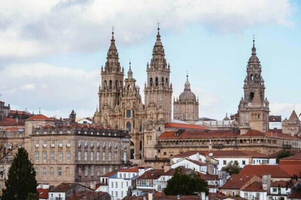 A historic building with multiple spires and domes, surrounded by residential buildings. - Exe Area Central (Santiago de Compostela)