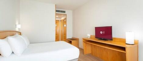 Una habitación de hotel con cama, televisión, escritorio y lámpara.
