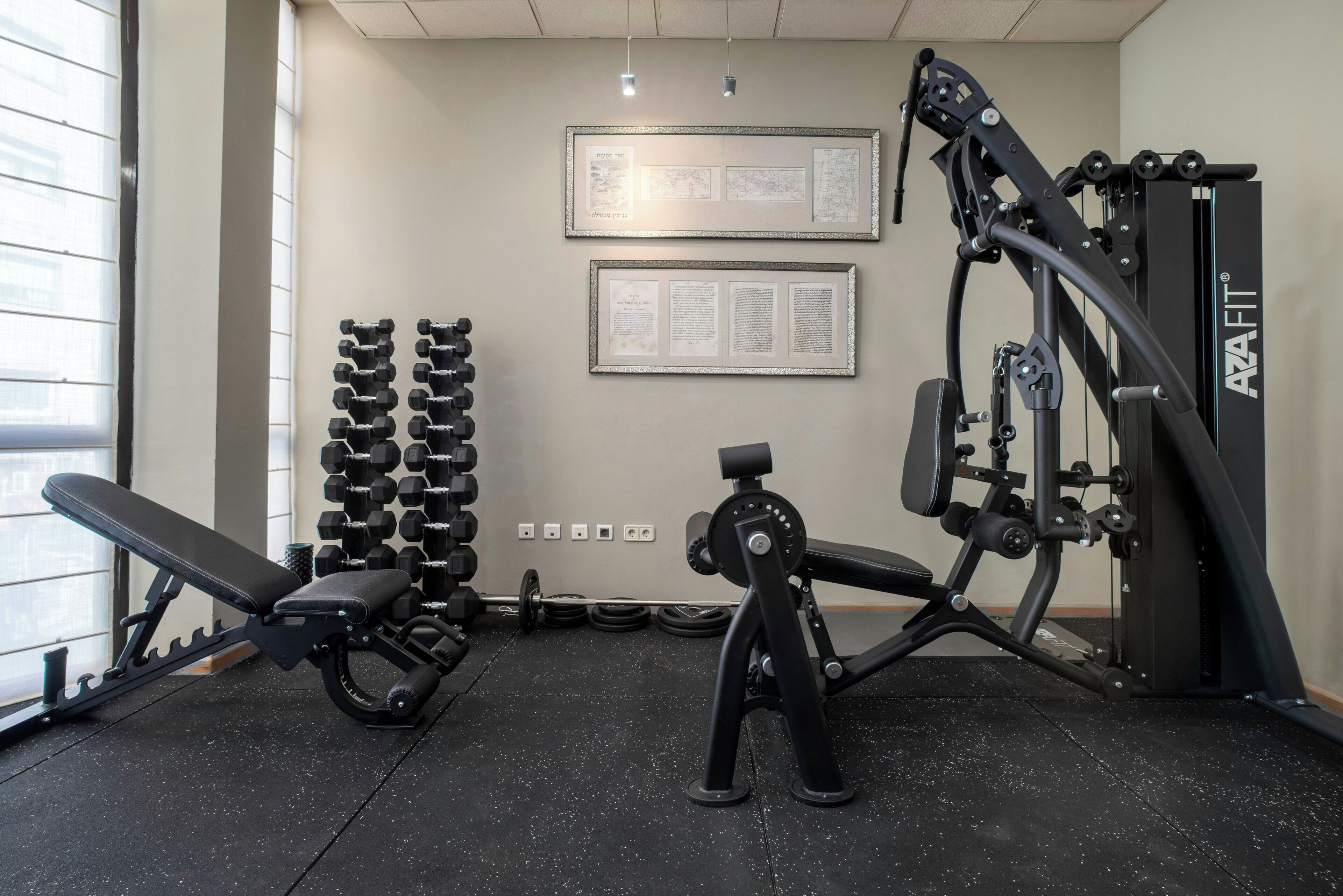 A gym with weight benches, dumbbells, and a cable machine.