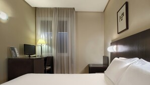 A hotel room with a bed, desk, chair, lamp, and a window with curtains. - Sercotel Tudela Bardenas (Tudela)
