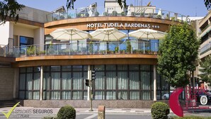 A hotel with a curved facade, large windows, and outdoor umbrellas. - Sercotel Tudela Bardenas (Tudela)