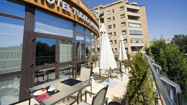 A hotel with outdoor seating, large windows, and a view of the city. - Sercotel Tudela Bardenas (Tudela)