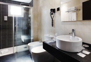 Un baño moderno con ducha envuelta en vidrio, inodoro blanco, lavamanos grande y espejo sobre el lavamanos.