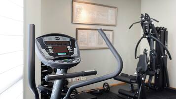 Equipamento de ginástica com visor digital e suporte de halteres fixado na parede.