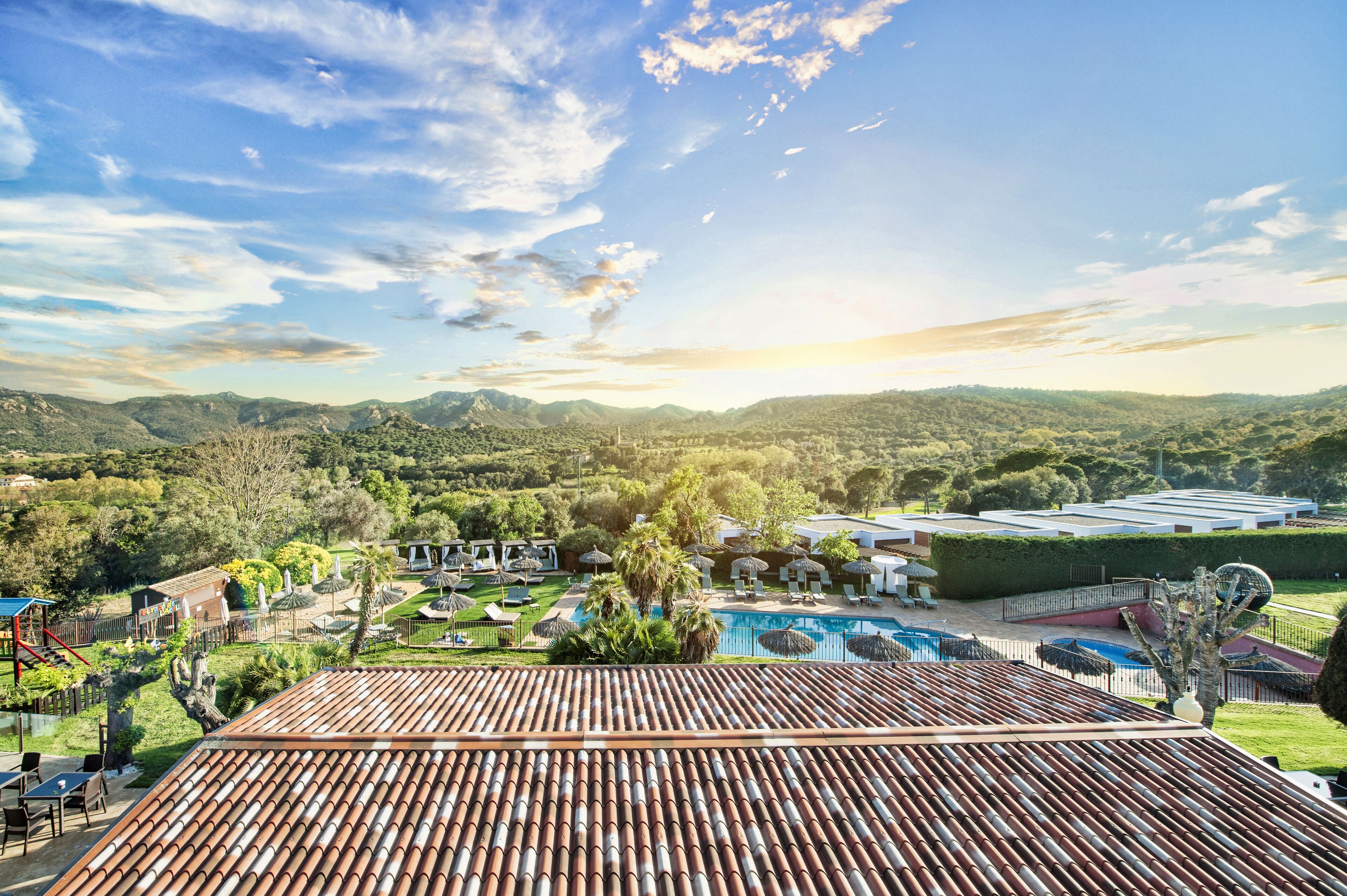 A resort with a swimming pool, outdoor seating, and a view of the mountains.