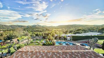 A resort with a swimming pool, outdoor seating, and a view of the mountains.