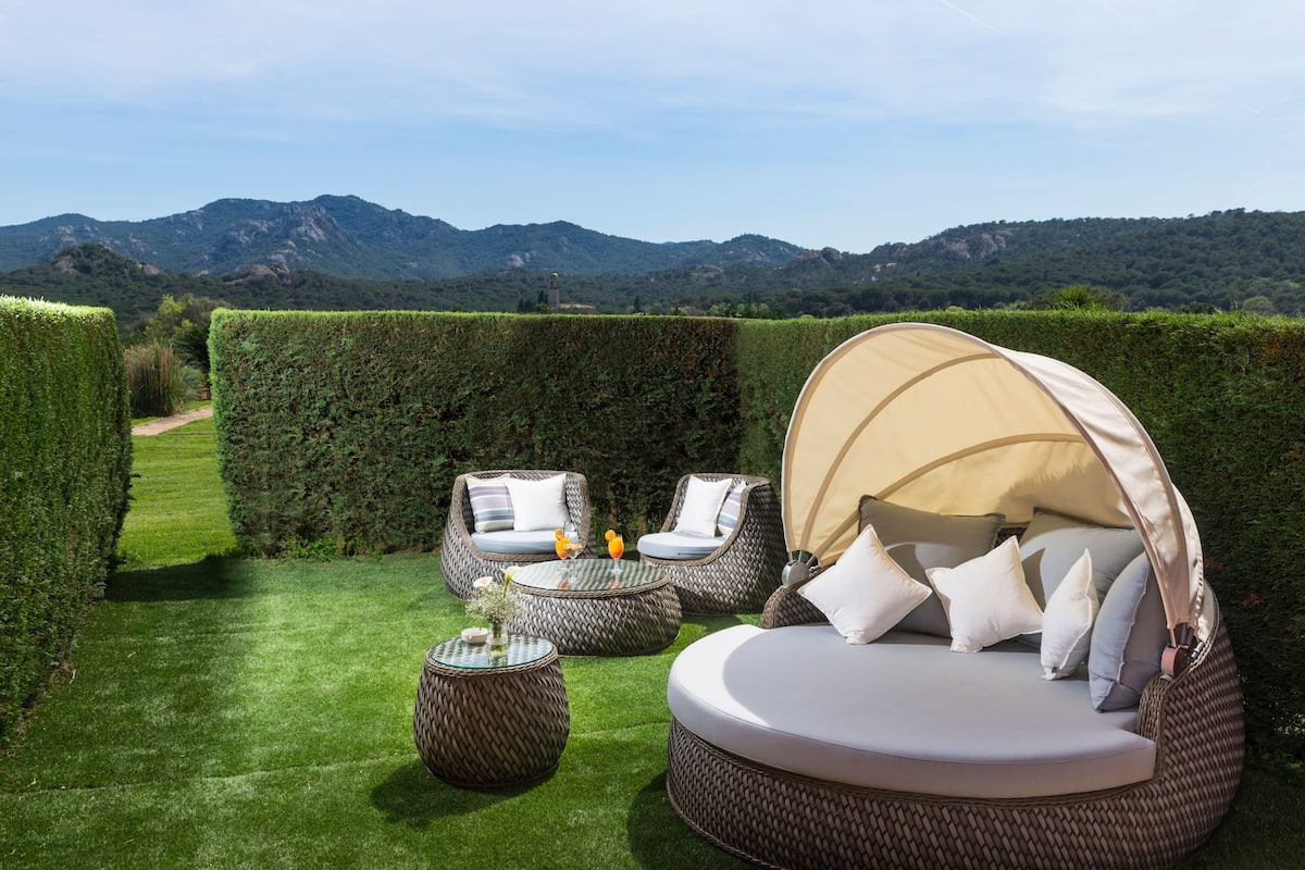 Ein Garten mit einer runden Sitzecke, einem Tisch und einem Baldachinbett.