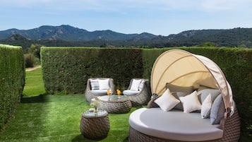 Un giardino con un'area salotto circolare, un tavolo e un letto a baldacchino.